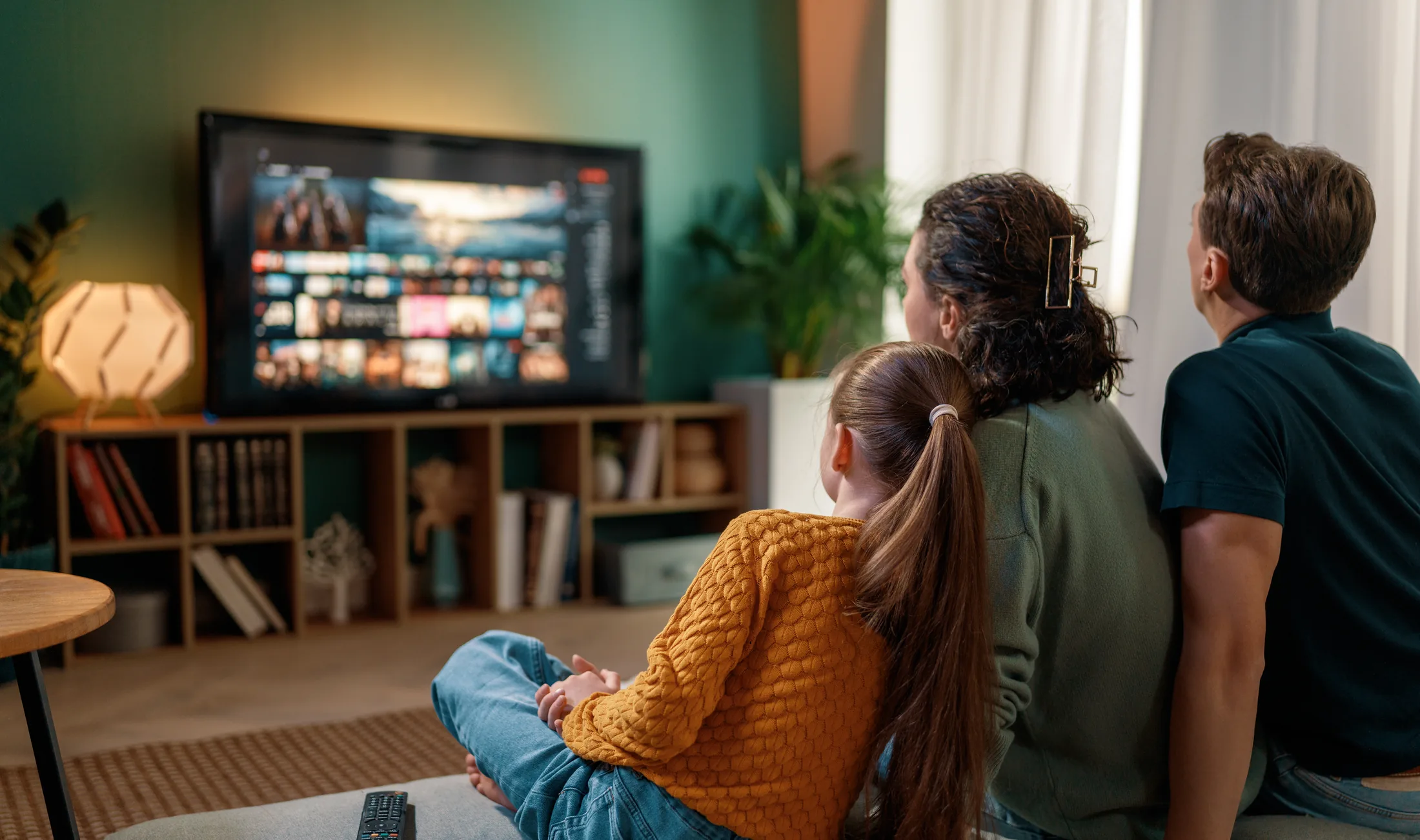 En familj sitter tillsammans i vardagsrummet och tittar på tv
